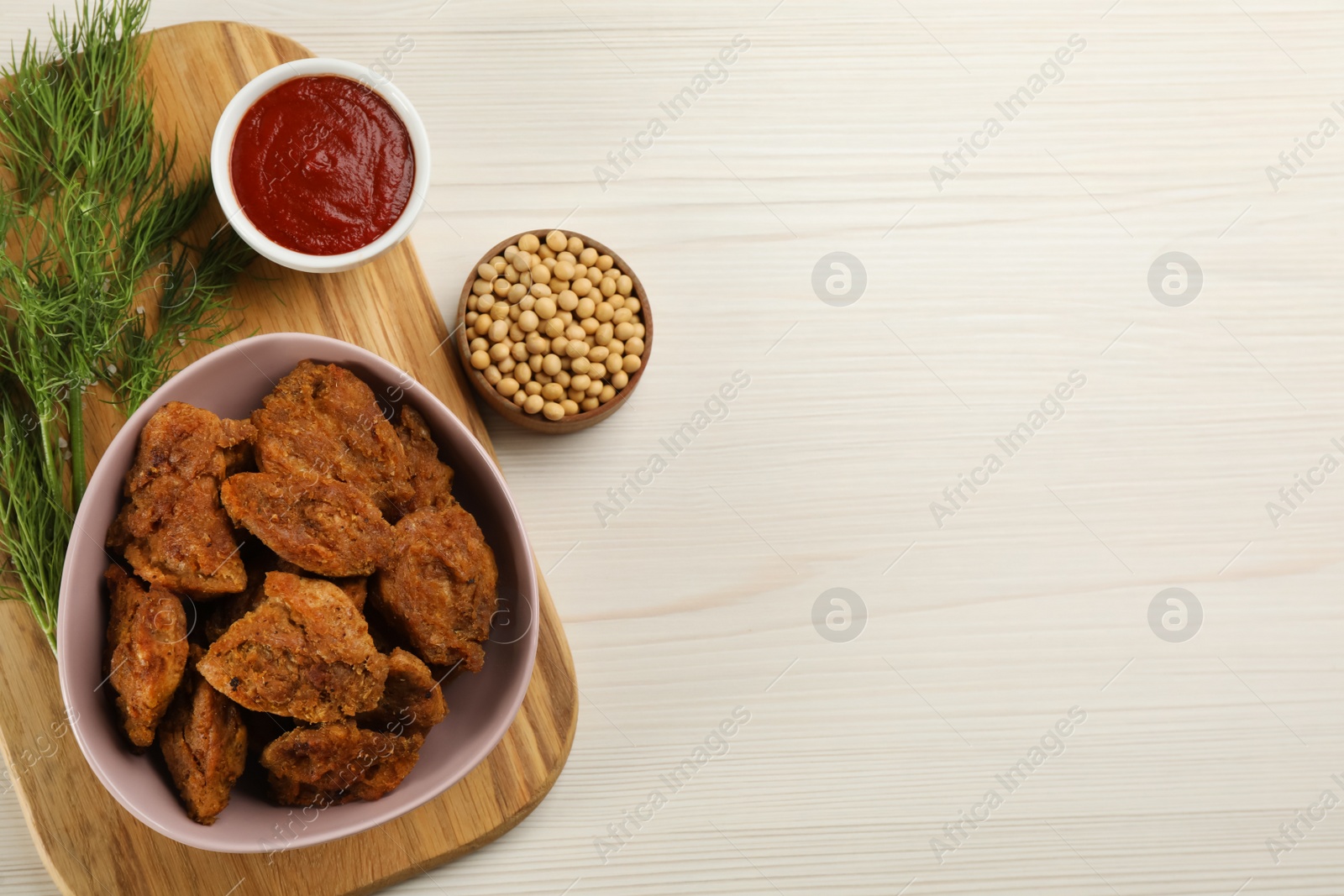 Photo of Cooked soy meat in bowl on white wooden table, flat lay. Space for text