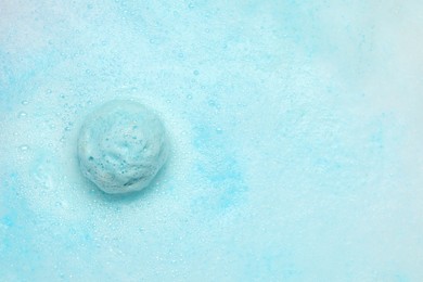 Light blue bath bomb dissolving in water. Space for text