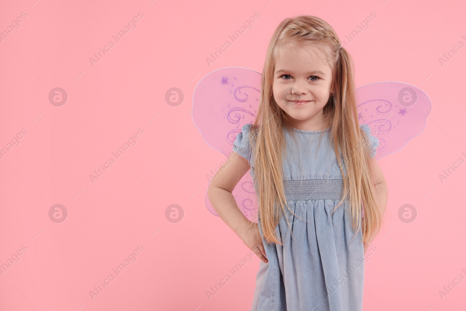 Photo of Cute little girl in fairy costume with violet wings on pink background, space for text