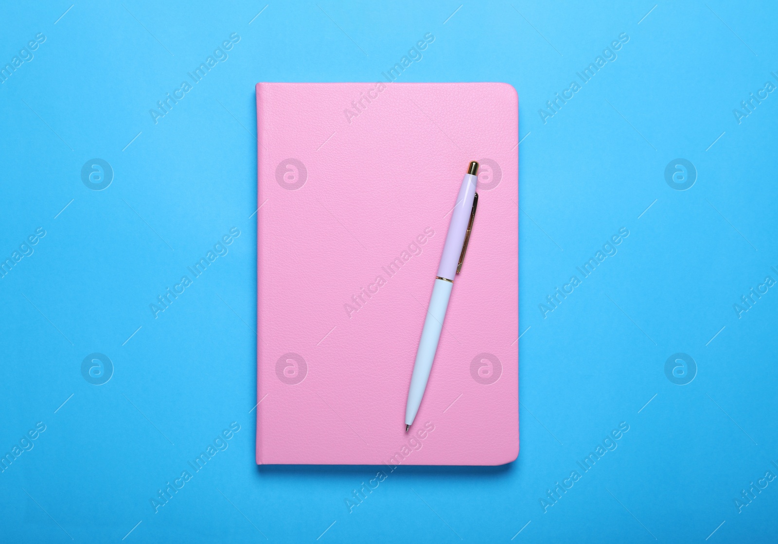 Photo of Closed pink notebook and pen on light blue background, top view