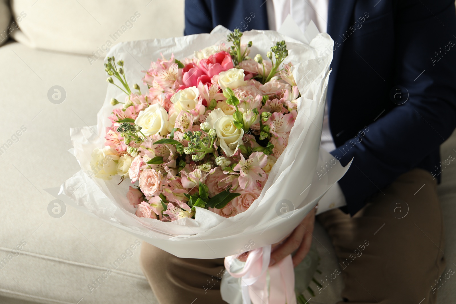 Photo of Man with beautiful bouquet of flowers on sofa indoors, closeup