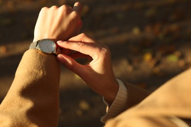 Photo of Woman checking time on watch outdoors, closeup. Being late concept