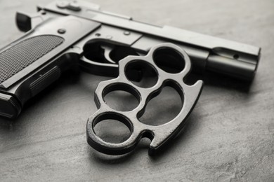 Photo of Brass knuckles and gun on black background, closeup