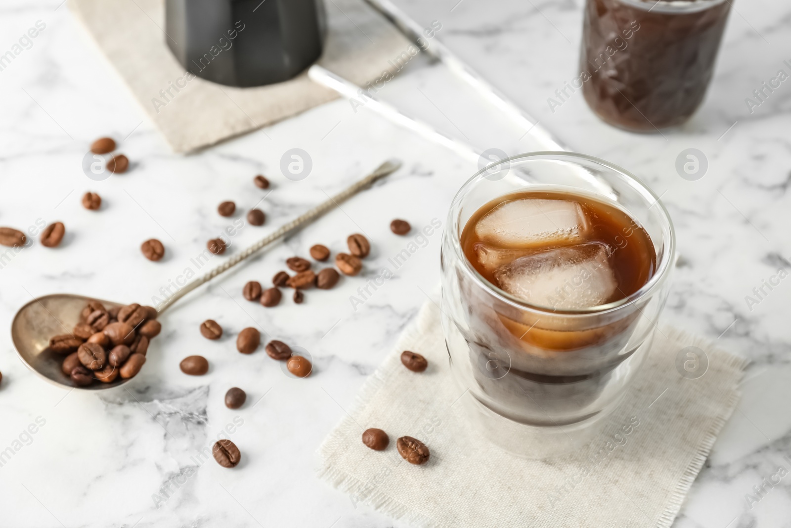 Photo of Glass with cold brew coffee and beans on light background