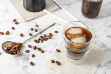 Glass with cold brew coffee and beans on light background