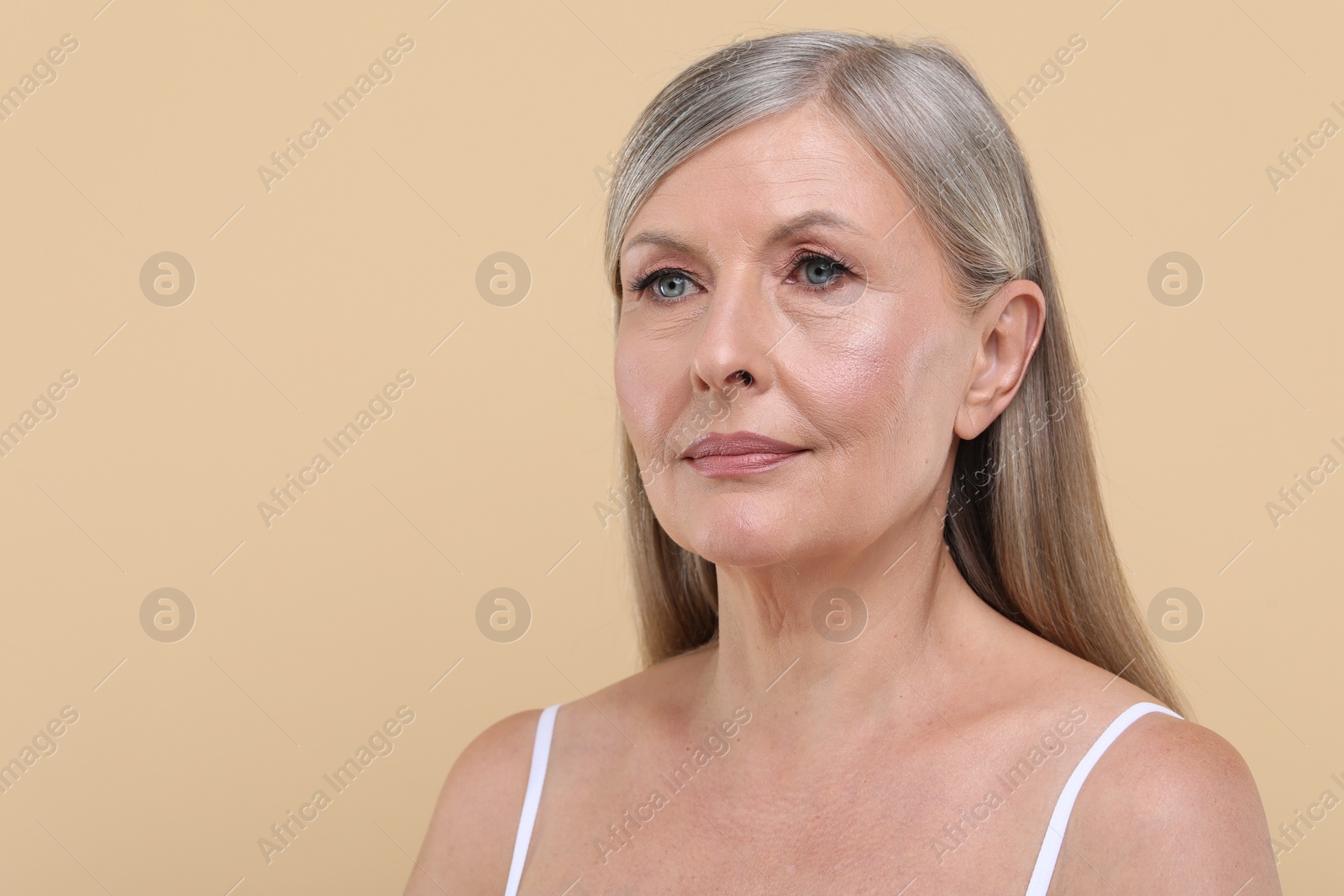 Photo of Portrait of beautiful senior woman on beige background. Space for text