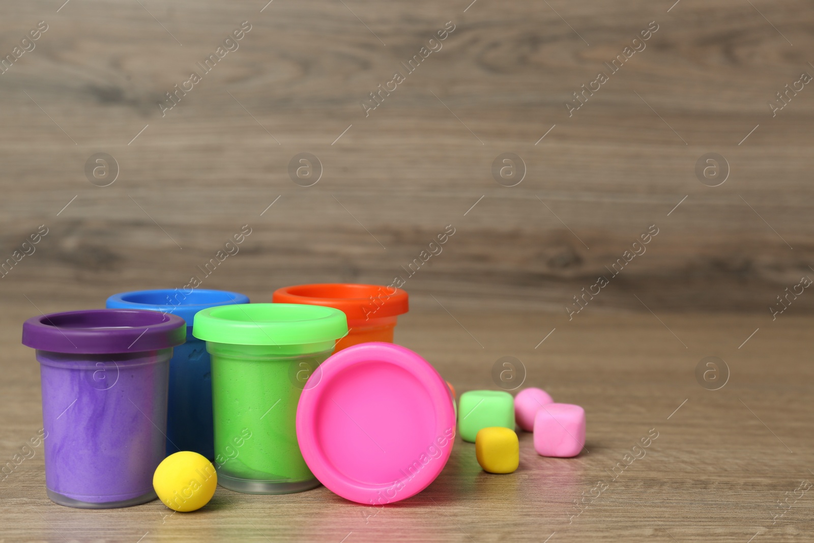 Photo of Different color play dough on wooden table. Space for text