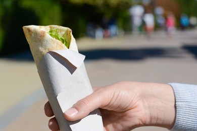 Woman holding delicious vegetable roll outdoors, closeup