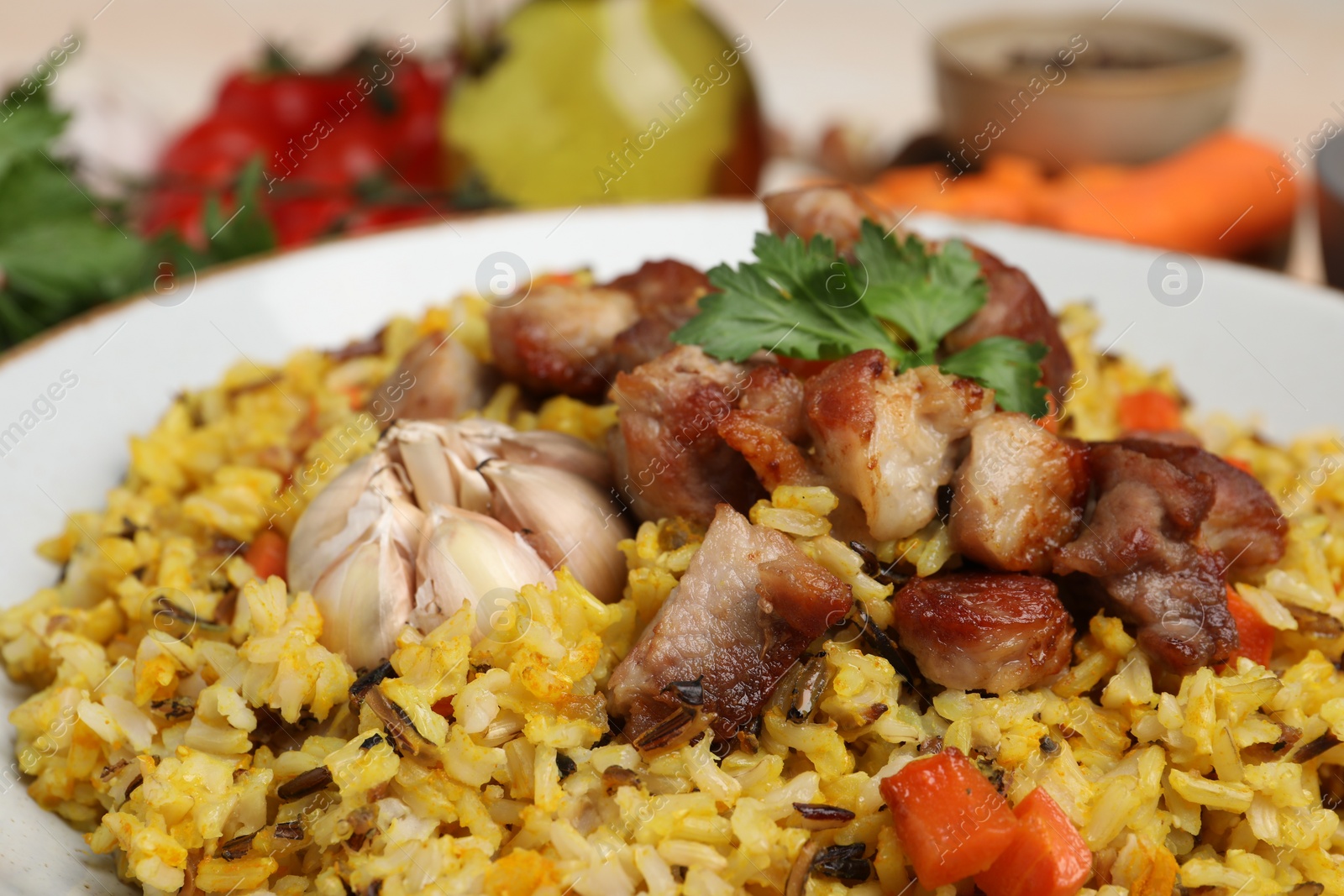 Photo of Delicious pilaf with meat, carrot and garlic on plate, closeup
