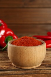Photo of Bowl of paprika with peppers on wooden table, closeup