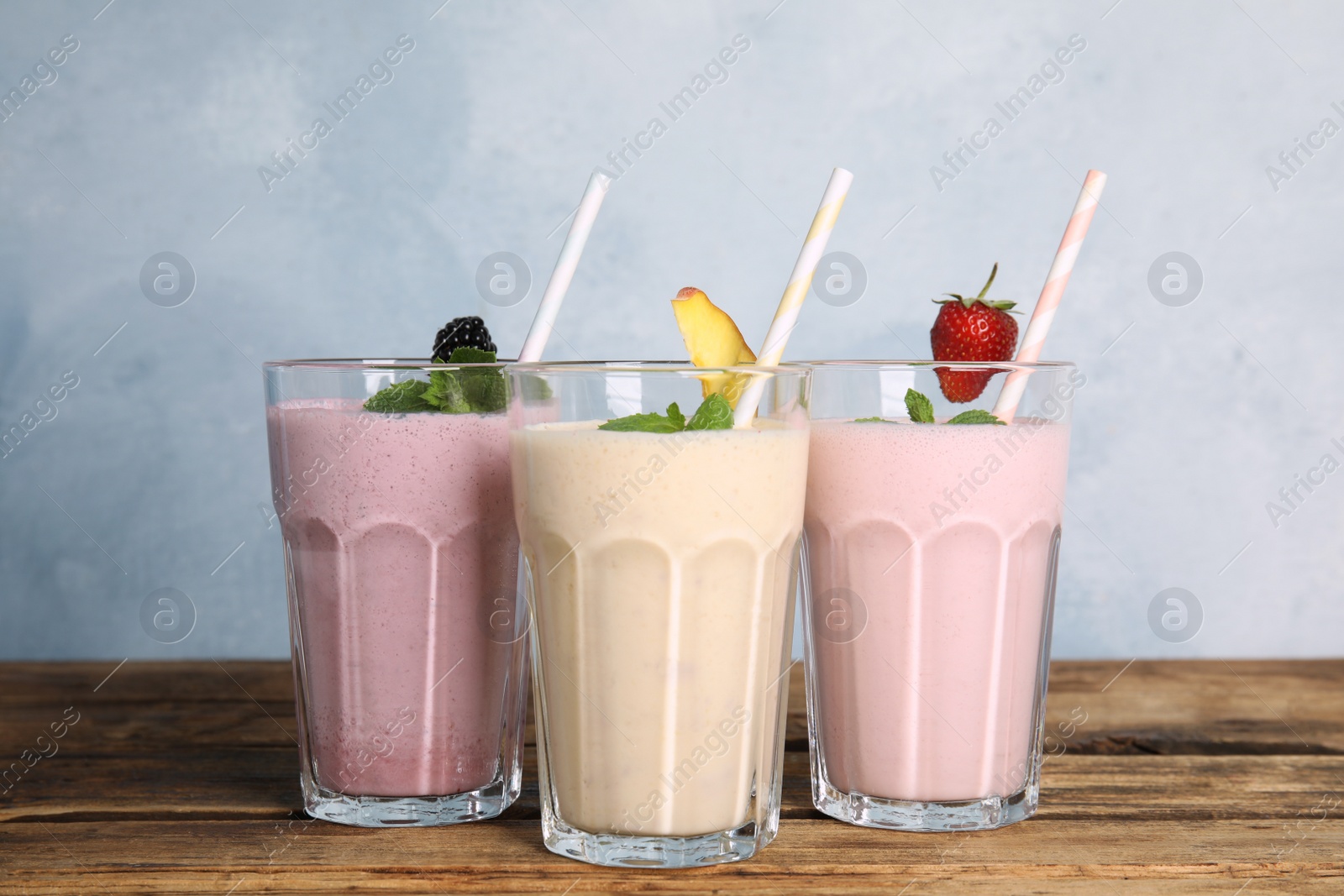 Photo of Different tasty milk shakes on wooden table