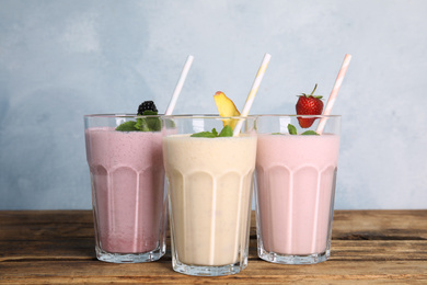 Photo of Different tasty milk shakes on wooden table