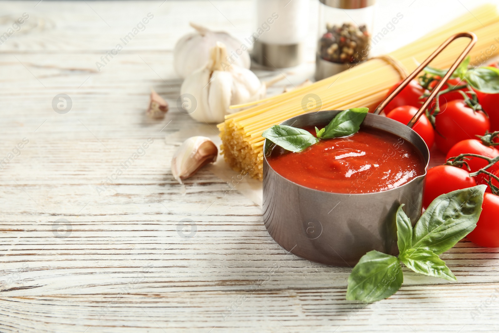 Photo of Pan of tasty tomato sauce served on wooden table. Space for text