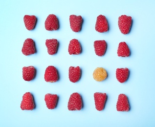 Flat lay composition with delicious ripe raspberries on blue background