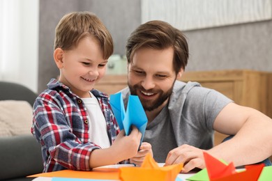Happy dad and son making paper figures at home