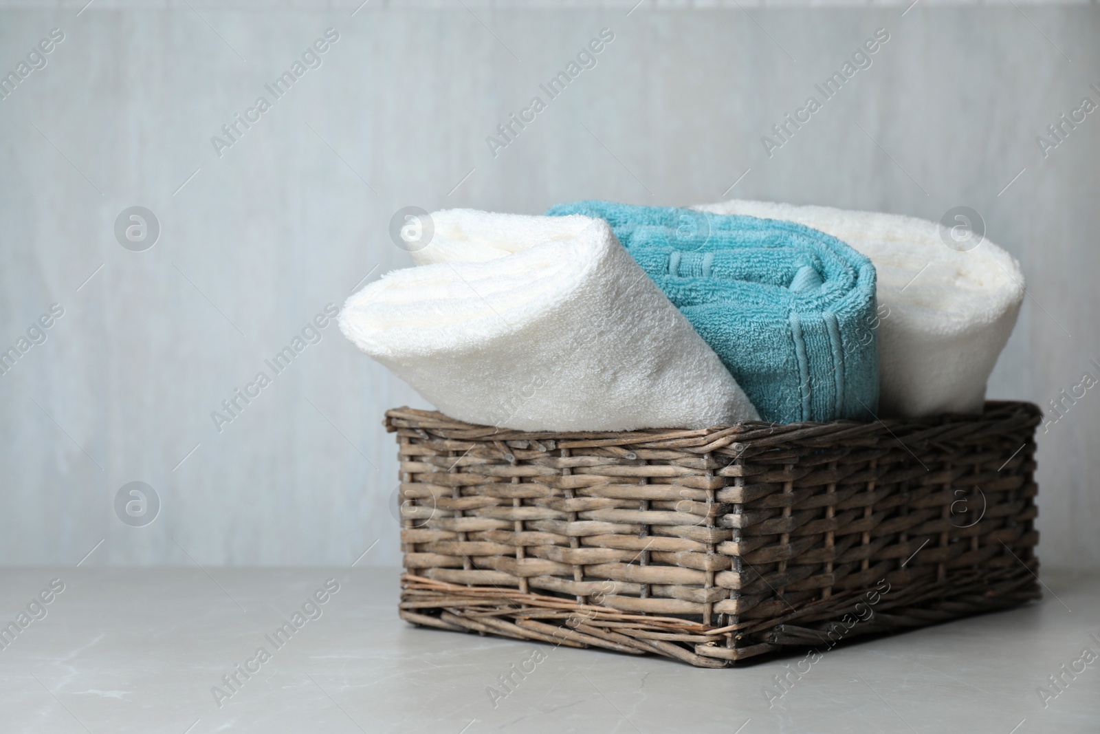 Photo of Basket with soft bath towels on table