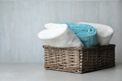 Basket with soft bath towels on table