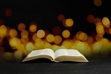 Image of Open Bible on wooblack den table, bokeh effect