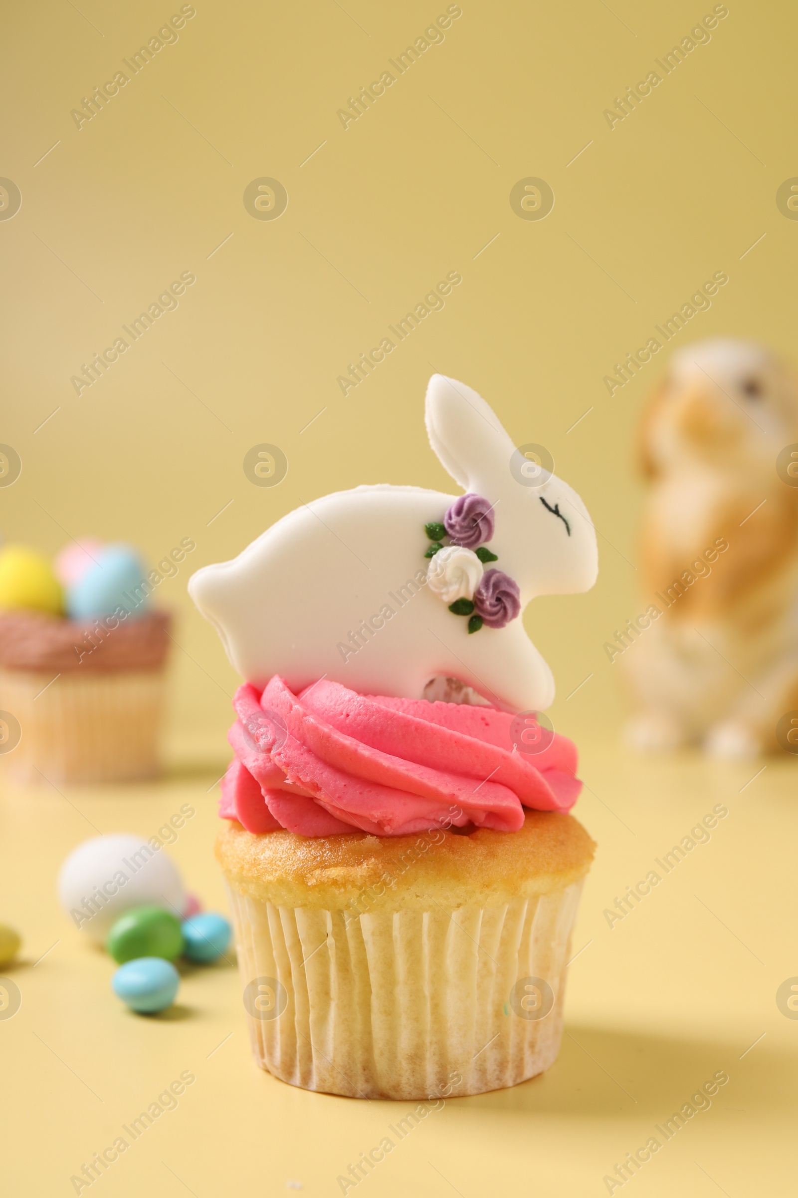 Photo of Tasty decorated Easter cupcake on pale yellow background