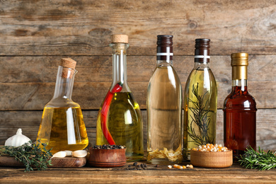 Photo of Different cooking oils in bottles on wooden table