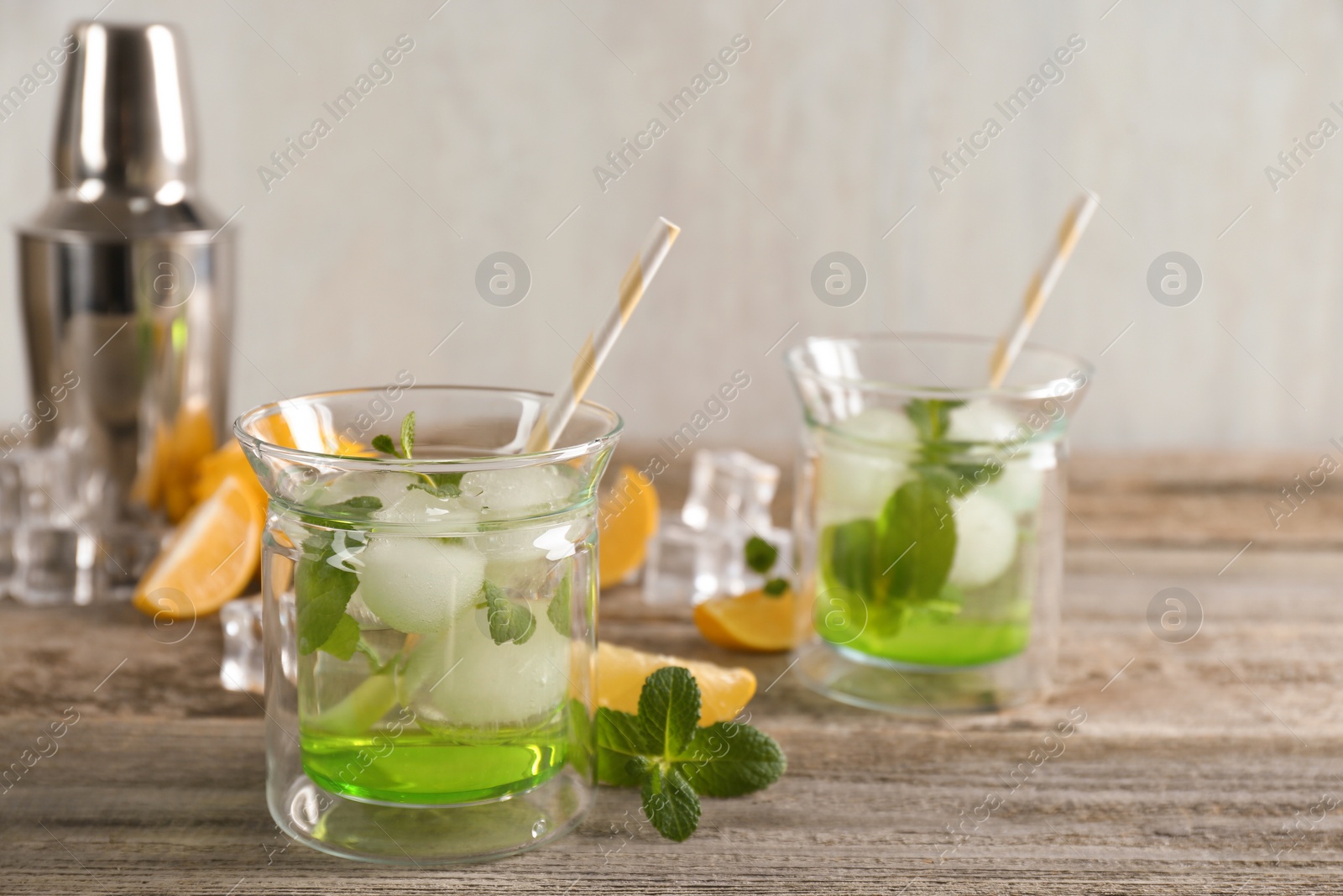 Photo of Delicious cocktails with mint and ice balls on wooden table