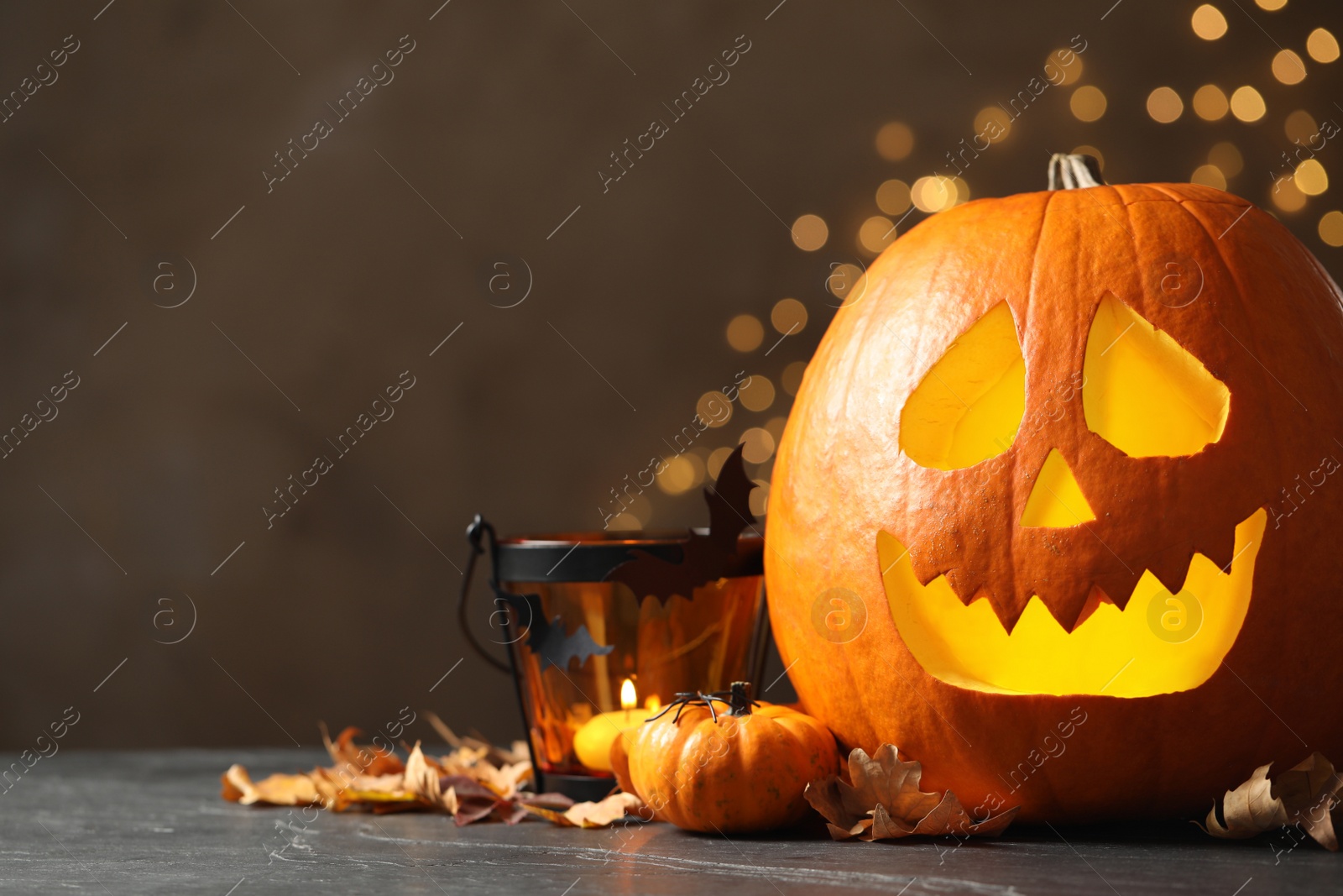 Photo of Pumpkin jack o'lantern and Halloween decor on table against blurred background, space for text