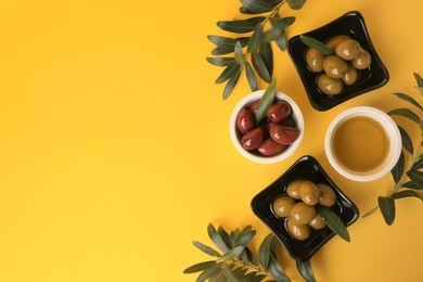 Bowl of oil, olives and tree twigs on yellow background, flat lay. Space for text