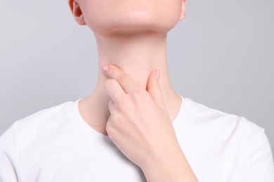 Photo of Woman with sore throat on light grey background, closeup
