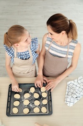 Photo of Mother and her daughter with cookie dough in kitchen