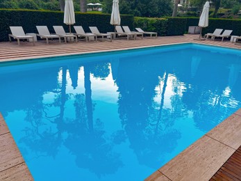 Photo of Outdoor swimming pool in luxury hotel on sunny summer day. Time for relax