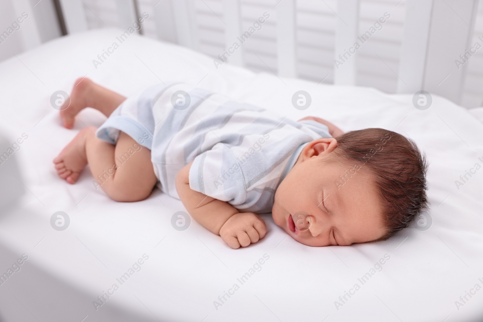 Photo of Cute newborn baby sleeping in crib. Bedtime
