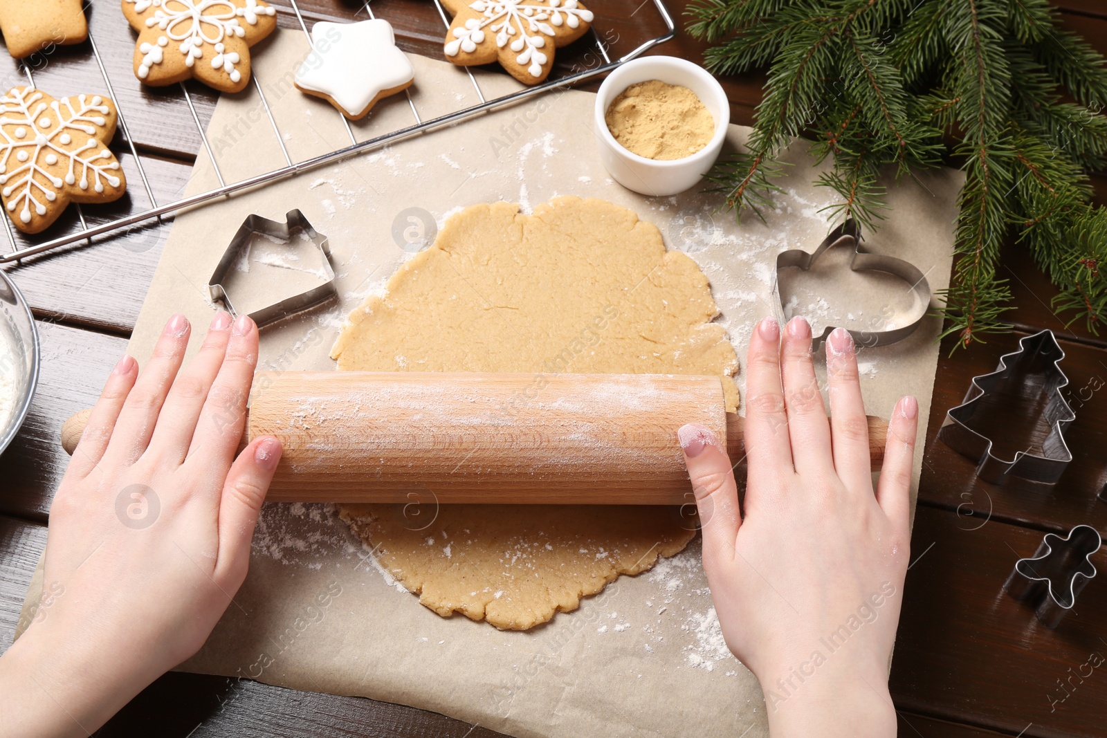 Photo of Making Christmas cookies. Woman rolling raw dough at wooden table, top view