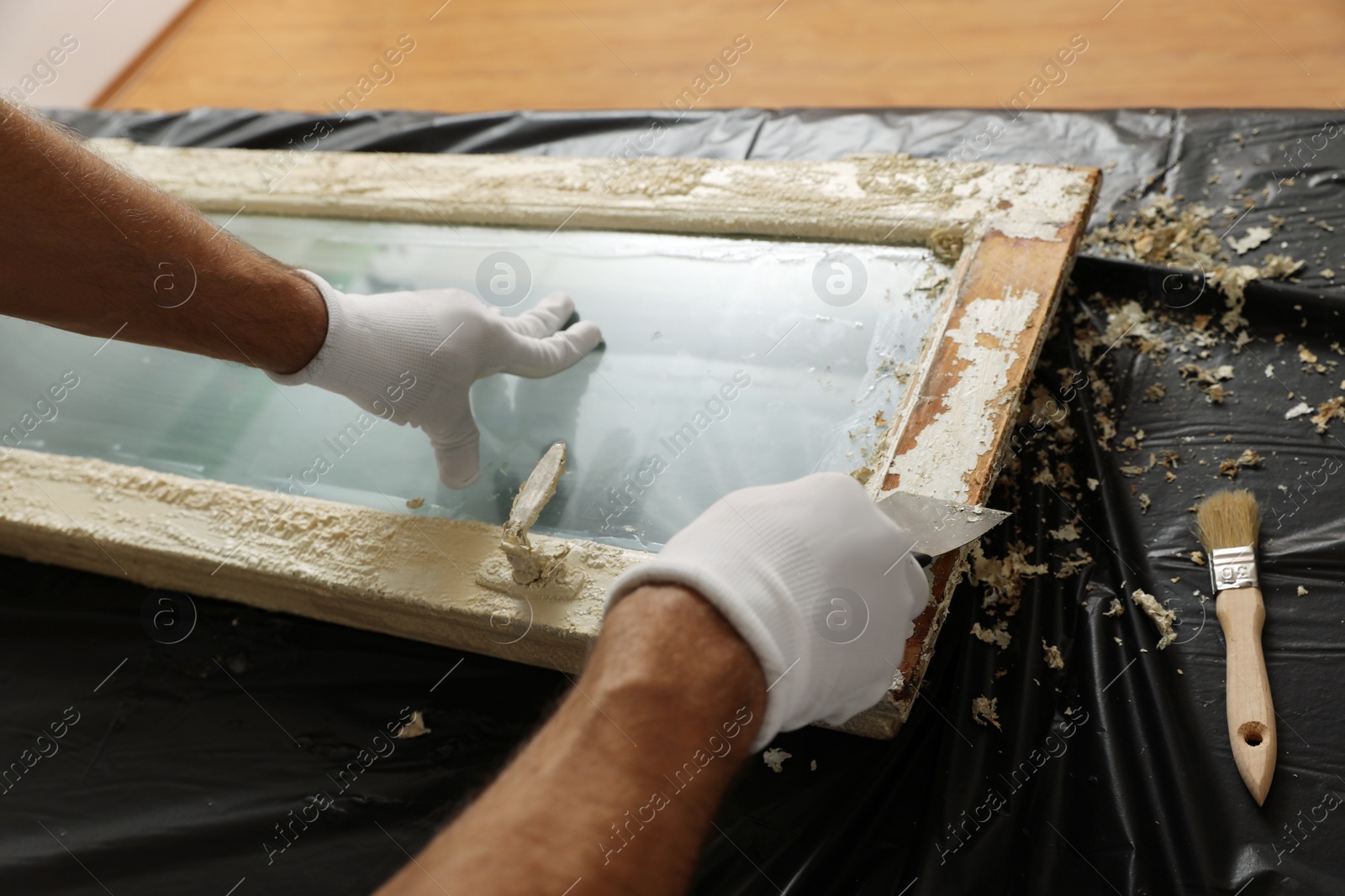 Photo of Man repairing old damaged window at table indoors, closeup