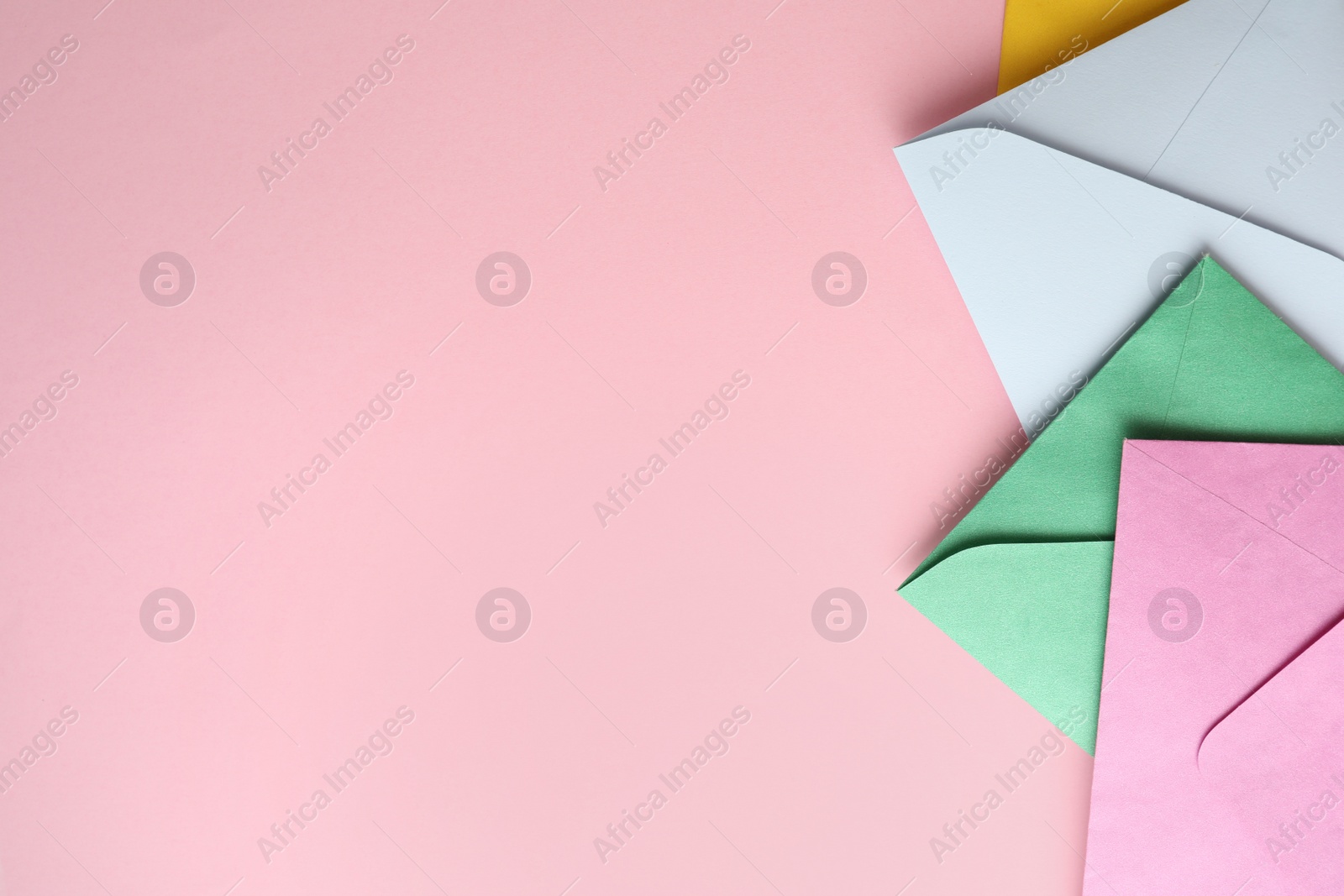 Photo of Colorful paper envelopes on pink background, flat lay. Space for text