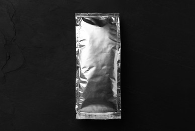 Blank foil package on black table, top view