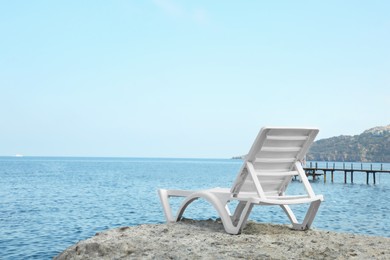 One lounge chair on beach near sea. Space for text