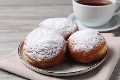 Photo of Delicious sweet buns and cup of tea on table, closeup