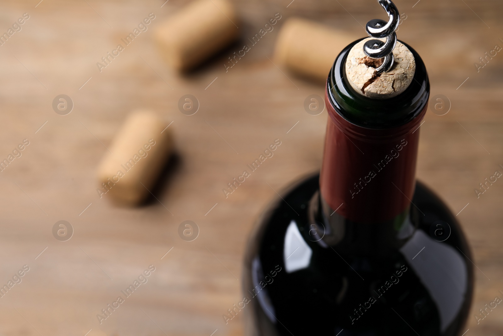 Photo of Opening wine bottle with corkscrew on table, closeup. Space for text