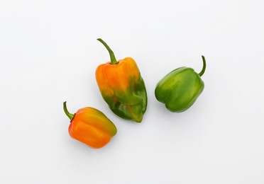 Different fresh raw hot chili peppers on white background, flat lay