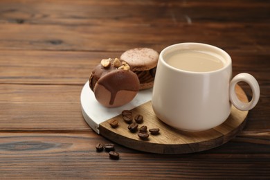 Cup of coffee and delicious macarons on wooden table. Space for text