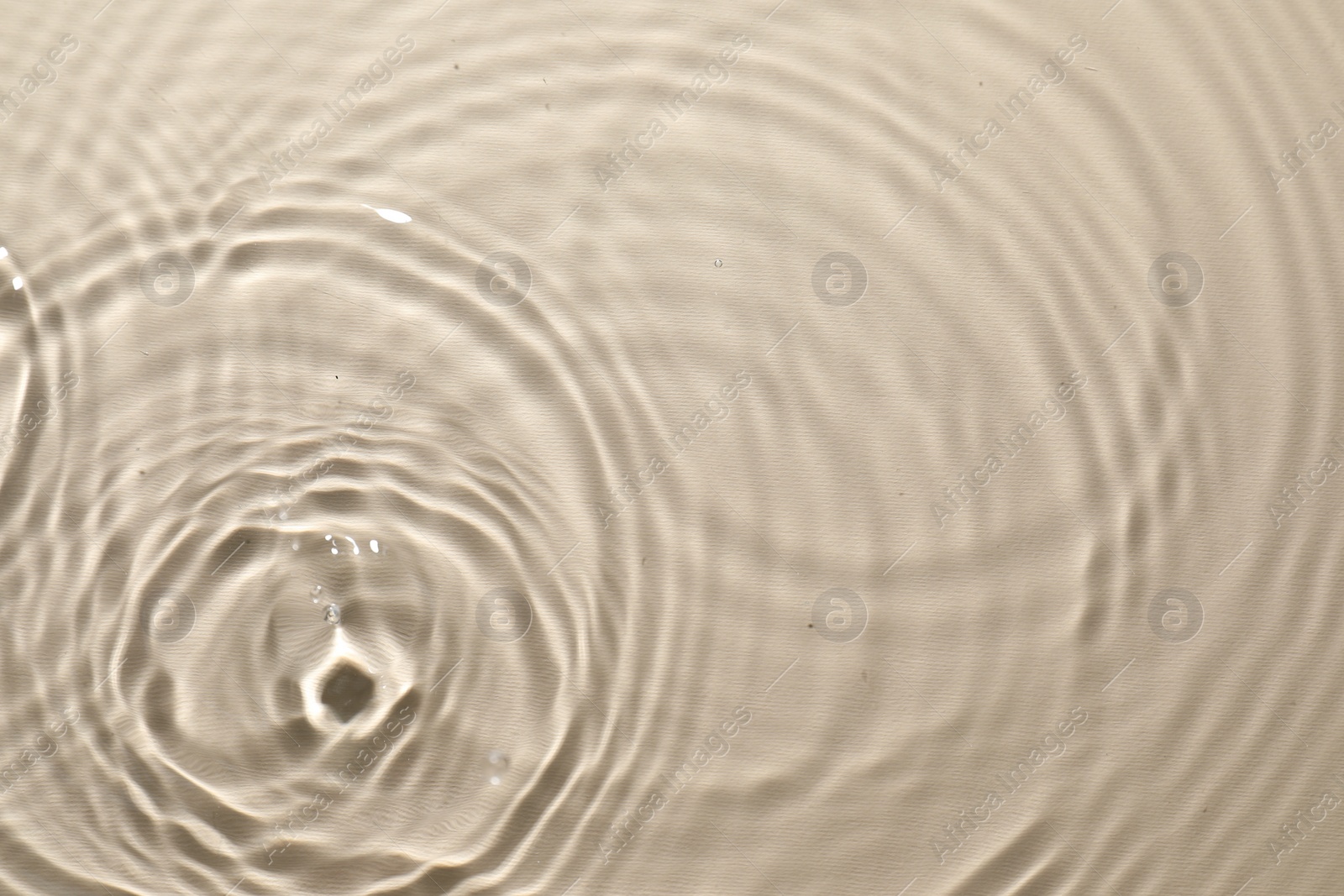 Photo of Rippled surface of clear water on beige background, top view