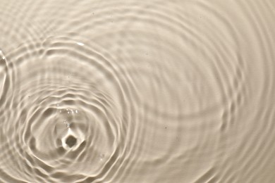 Photo of Rippled surface of clear water on beige background, top view