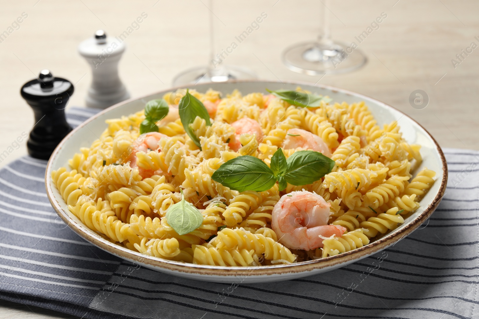 Photo of Plate of delicious pasta with shrimps, basil and parmesan cheese on table, closeup