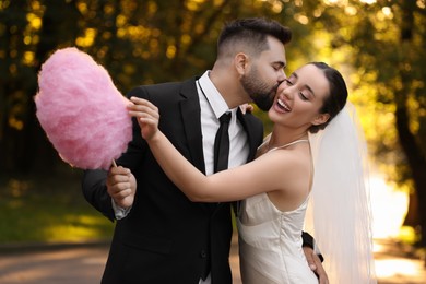 Happy newlywed couple with cotton candy in park