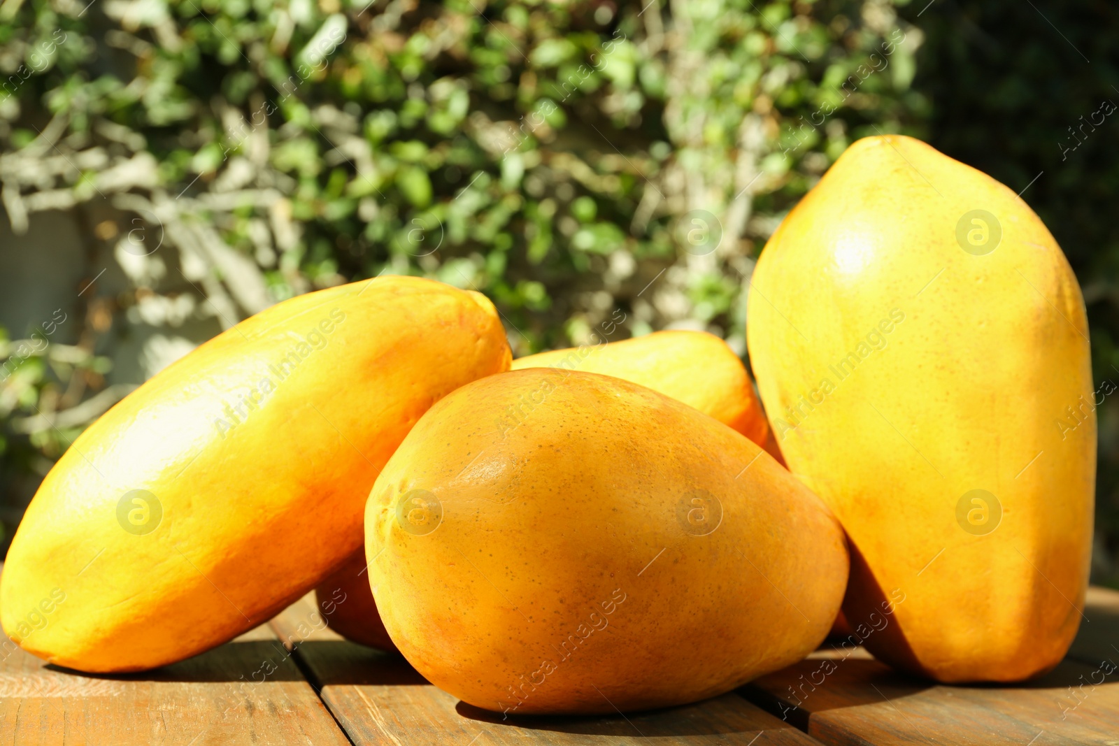 Photo of Fresh ripe papaya fruits on wooden table outdoors