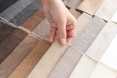 Photo of Young woman choosing among upholstery fabric samples, closeup. Interior design