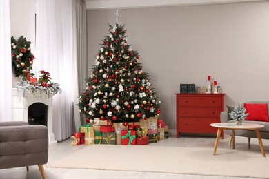 Photo of Beautiful Christmas tree and gifts near fireplace in festively decorated living room