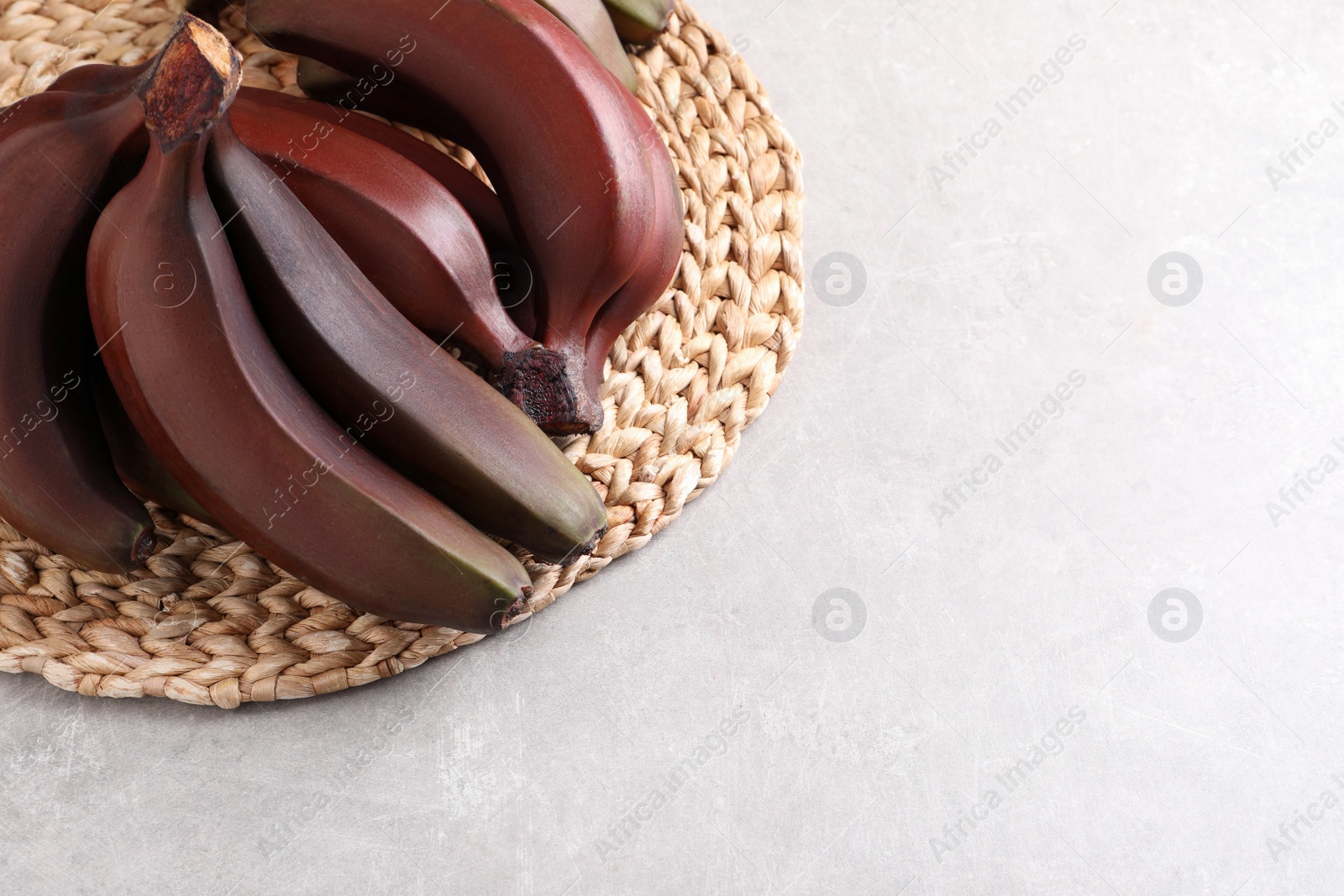 Photo of Delicious red baby bananas on light table, above view. Space for text