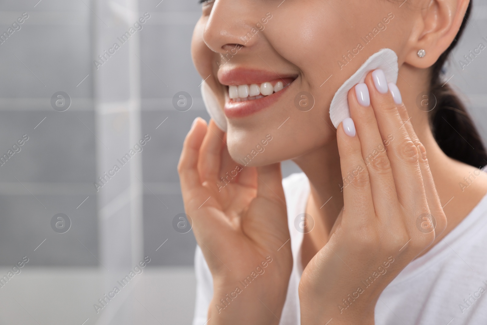 Photo of Young woman using cotton pads with micellar water in bathroom, closeup. Space for text
