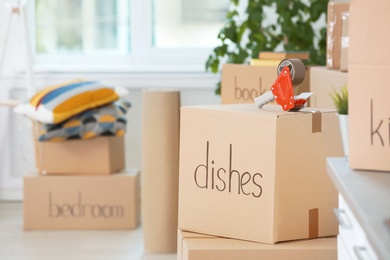 Photo of Cardboard boxes and adhesive tape dispenser indoors. Space for text
